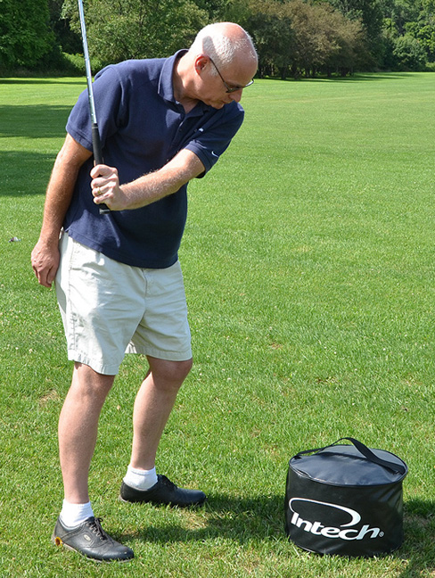 a person getting ready to strike the Intech Golf Impact Bag with a golf club