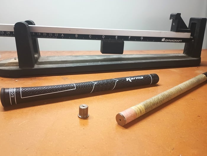 shaft counterweight inside a graphite shaft with grip tape and a swing weight scale in the back ground